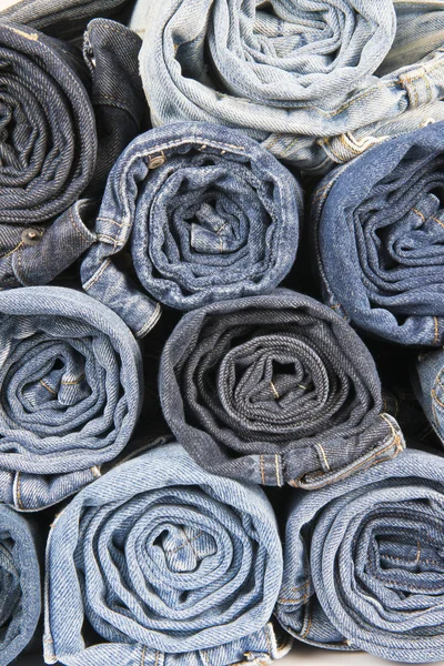 Rolls of different worn blue jeans stacked — Stock Photo, Image