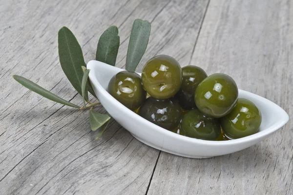 Untertasse mit Oliven auf einer Holzoberfläche — Stockfoto