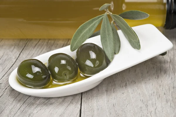 Olive oil and olives on a wooden surface — Stock Photo, Image