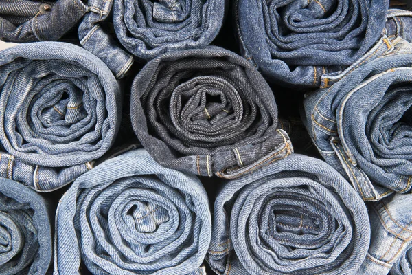 Rolls of different worn blue jeans stacked — Stock Photo, Image