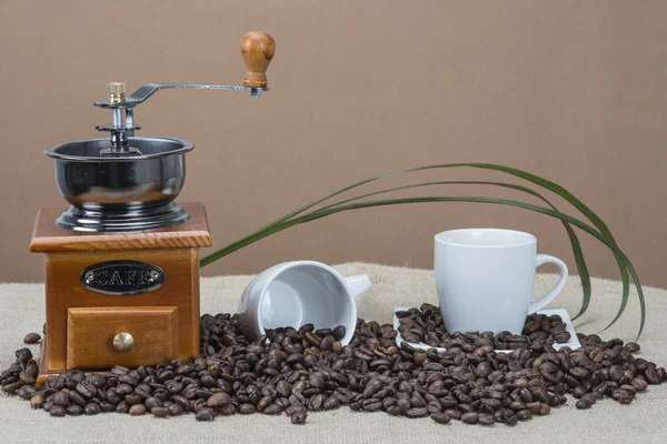 Moedor de café e copos em algum feijão — Fotografia de Stock