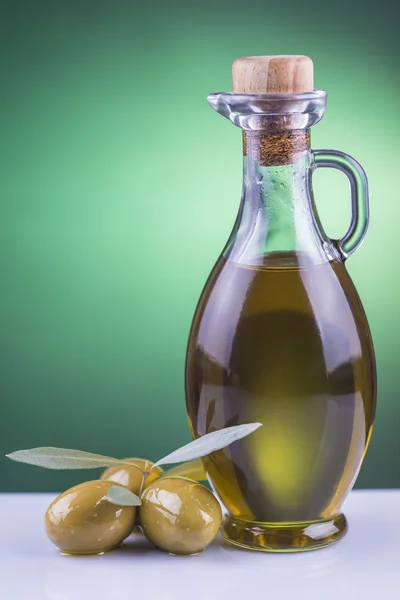 Garrafa de azeite e azeitonas sobre fundo verde — Fotografia de Stock