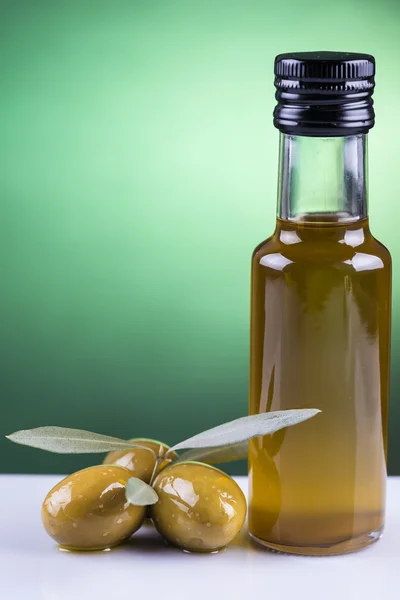 Bottiglia di olio e olive su fondo verde — Foto Stock