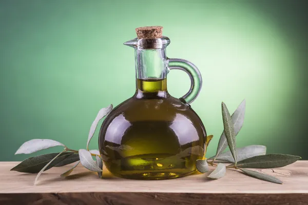 Бутылка оливкового масла с зеленым фоном — стоковое фото