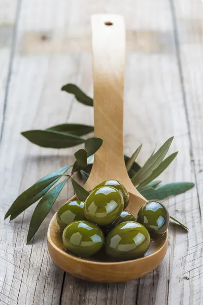Wooden spoon with olives and oil — Stock Photo, Image
