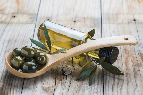 Bottiglia di olio d'oliva e un cucchiaio con olive — Foto Stock