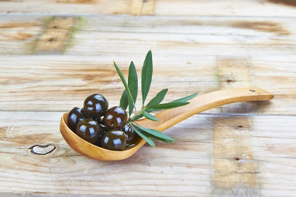 Drewnianą łyżką z oliwek na stole — Zdjęcie stockowe