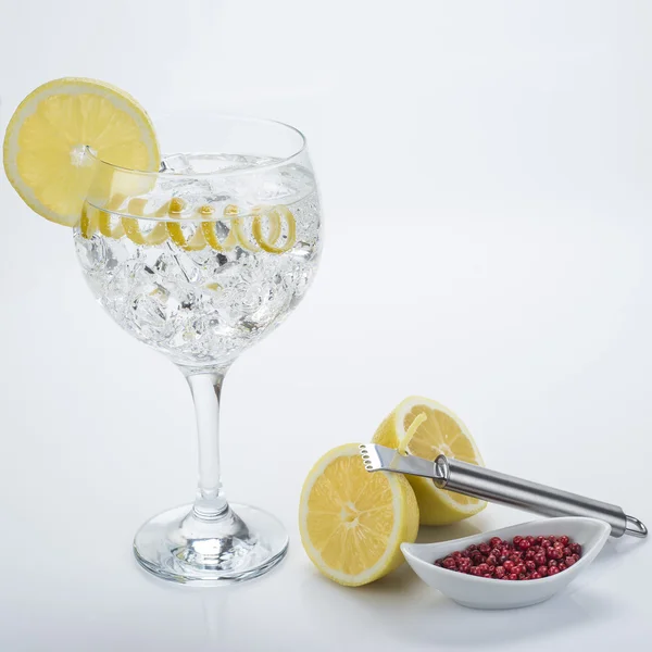 Gin and tonic with pink pepper and lemon twist — Stock Photo