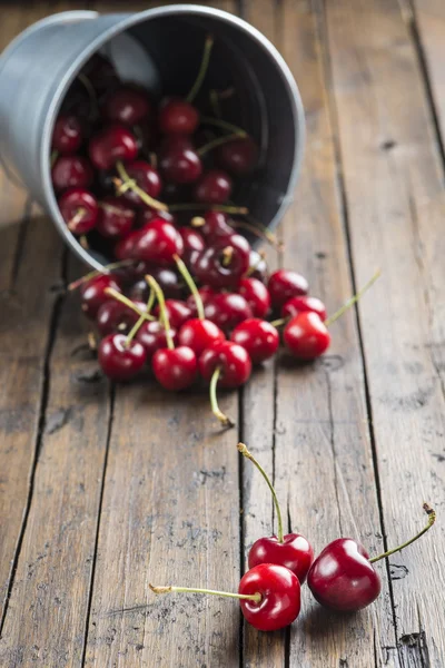 Little brass bucket of cherries on a table — Stock Photo, Image