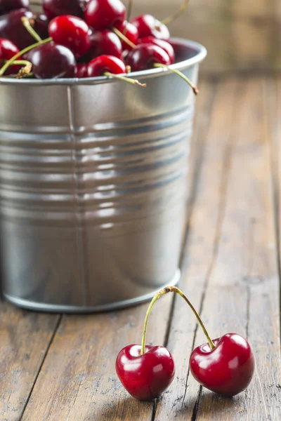 Little brass bucket of cherries on a table — Stock Photo, Image