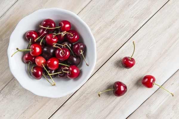 Cuenco blanco de cerezas en la mesa — Foto de Stock