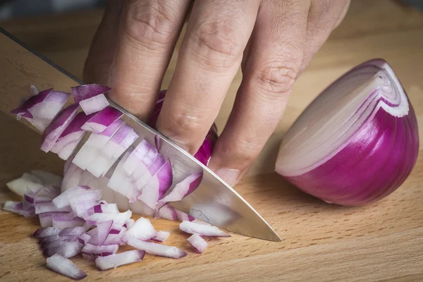 Chef choppig una cebolla roja con un cuchillo — Foto de Stock