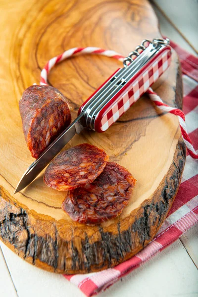 Cortar Chorizo Con Cuchillo Suizo Una Tabla Madera Vestir Vichy — Foto de Stock