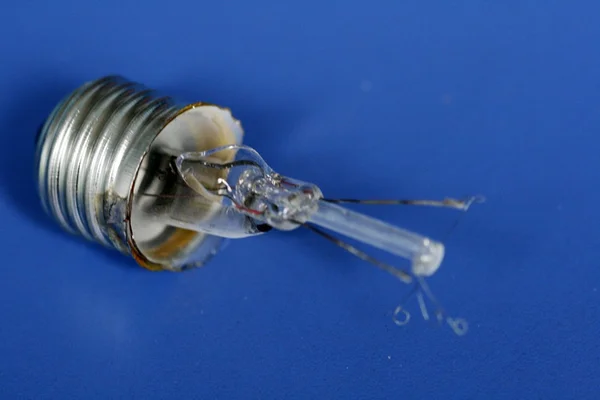 Broken light bulb on blue background