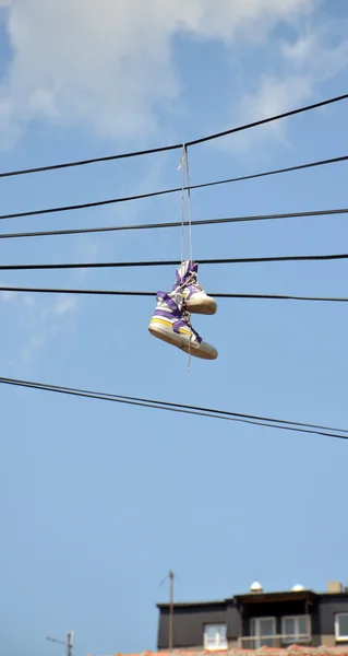 Sneakers hängande från elektrisk tråd mot en blå himmel — Stockfoto