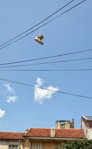 Zapatillas colgando de alambre eléctrico contra un cielo azul — Foto de Stock