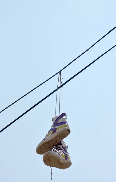 Sneakers hängande från elektrisk tråd mot en blå himmel — Stockfoto