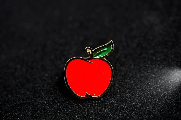 Red apple pin badge on black background image