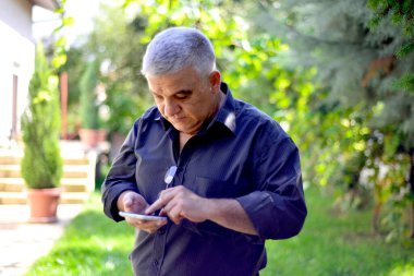 Yaşlı bir adam cep telefonuyla konuşuyor. Dedem akrabalarıyla veya torunlarıyla konuşuyor. Yetişkin bir erkek arıyor ya da cevap veriyor.