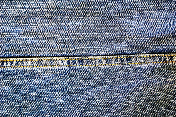 Background on the theme of denim clothing. Denim fabric with elements of seams.