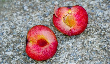 Juicy red Plum fruits with cut in half on concrete background