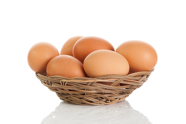Brown eggs in the basket on white.
