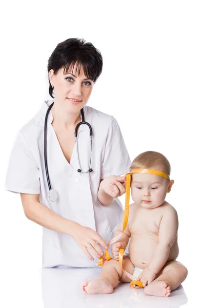 Schöne Ärztin und Baby auf weißem Hintergrund. Maßnahmen des Arztes Stockbild