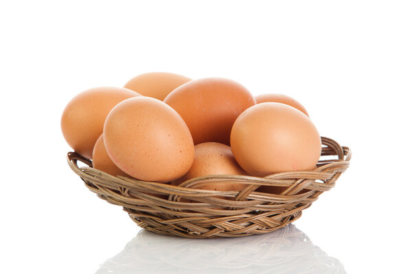 Brown eggs in the basket on white.