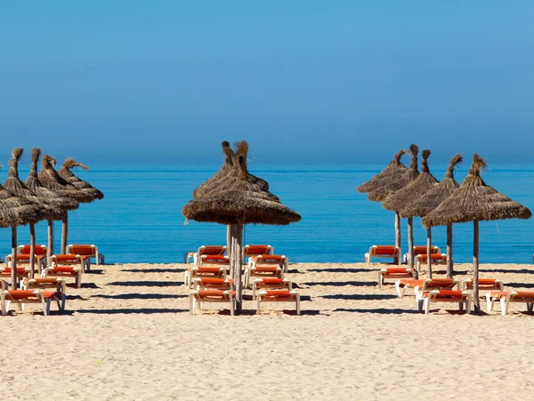 Scenerii tropikalnej plaży z parasolem i leżakami. parasol — Zdjęcie stockowe