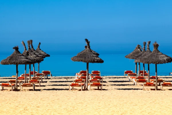 Tropische Strandlandschaft mit Sonnenschirm und Liegestühlen. Regenschirm a — Stockfoto