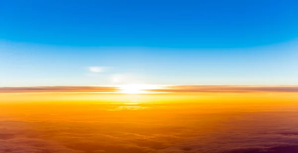 Puesta de sol sobre las nubes. Vista del atardecer desde la ventana del avión — Foto de Stock