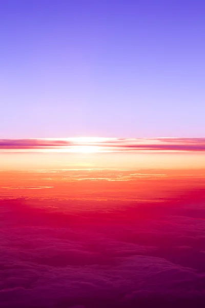 Puesta de sol sobre las nubes. Vista del atardecer desde la ventana del avión — Foto de Stock