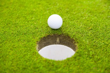 golf ball on lip of cup.