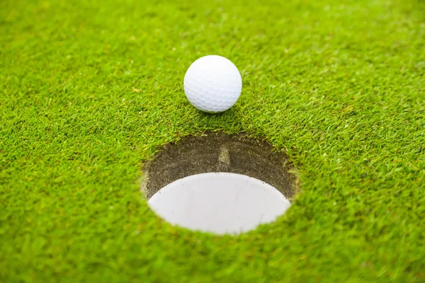 Golf ball on lip of cup. — Stock Photo, Image