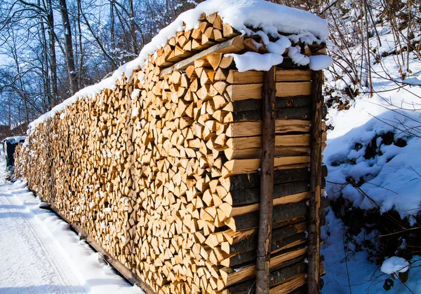 Firewood stacked in winter. Wood pile with snow stacked for fir — Stock Photo, Image