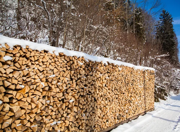 Firewood stacked in winter. Wood pile with snow stacked for fir — Stock Photo, Image