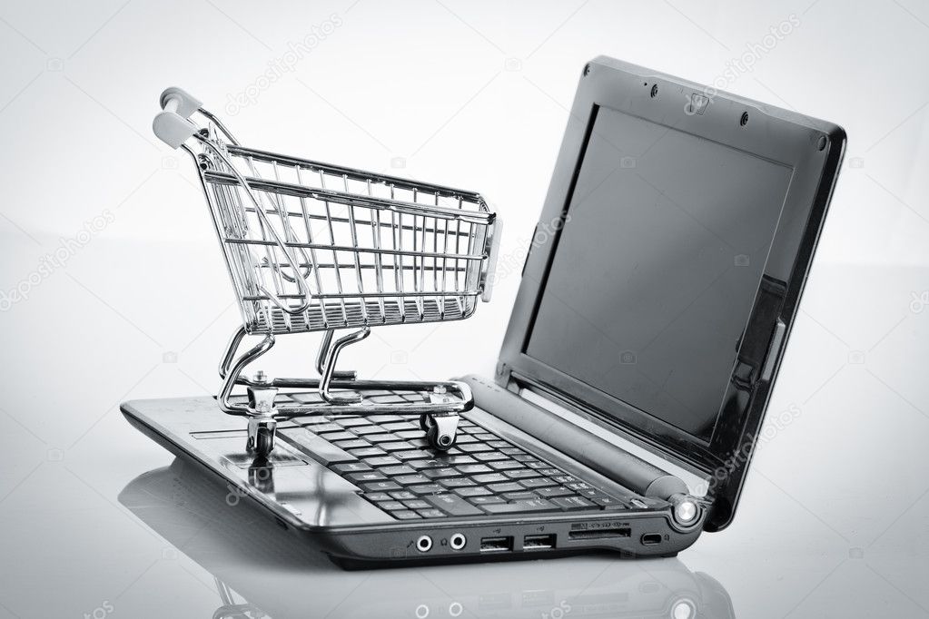 Online shopping. Shopping cart with notebook on the white.