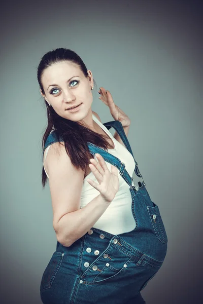 Pregnant girl in denim overalls — Stock Photo, Image