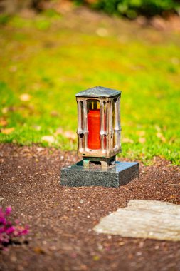 Çiçekli bir mezarda mumla birlikte mezar ışığı