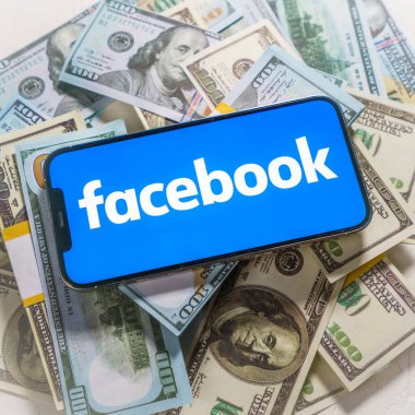 Berlin, Almanya - 2 Şubat 2022: iPhone 12 Pro Max FACEBOOK META şirket logosu ABD dolarları üzerine yerleştirildi