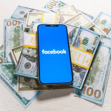 Berlin, Almanya - 2 Şubat 2022: iPhone 12 Pro Max FACEBOOK META şirket logosu ABD dolarları üzerine yerleştirildi