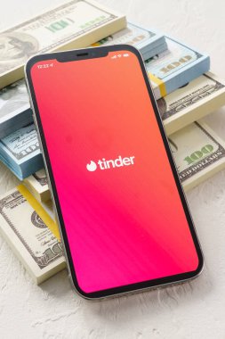 Sochi, Rusya - 1 Ekim 2021: iPhone 12 Pro Max çevrimiçi internet ağı hizmetleri Tinder ekranda ve dolar parasıyla