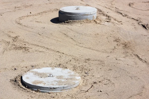 Concrete manholes on sand — Stock Photo, Image