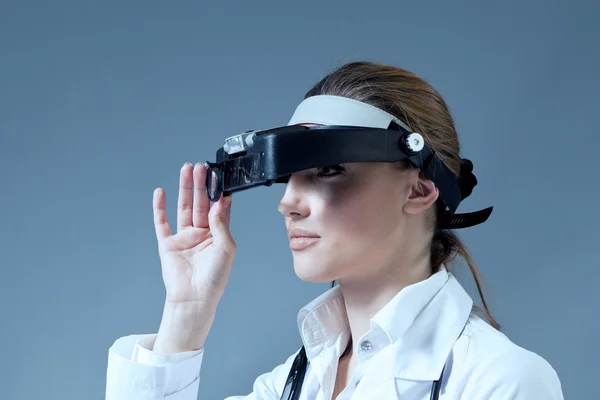 Young female doctor wearing magnifying glass equipment on her had — Stock Photo, Image