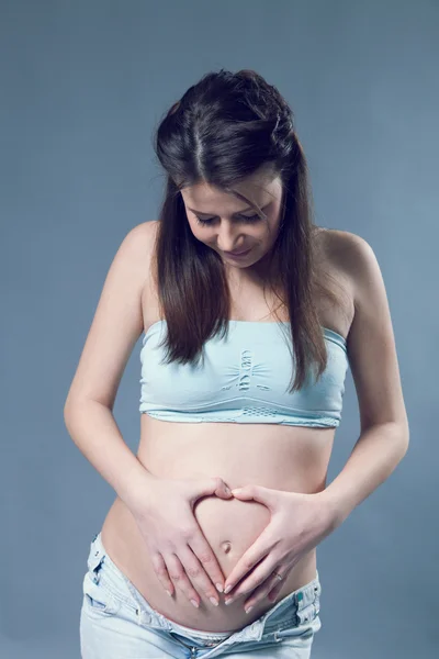 Beautiful pregnant white woman wearinglight blue top and jeans — Stock Photo, Image