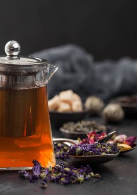 Yeşil ve siyah, şekerli ve cam çaydanlıklı çay kaşıklı ve fincanlı çay ve siyah arka planda kaşık