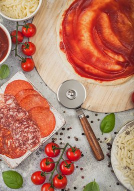 Çiğ hamurlu pepperonili pizza pişirme hazırlığı, çarklı baharatlı sucuk ve taze domatesli fesleğen, peynir ve domates ezmeli tabak..