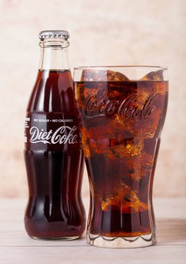 Londra, İngiltere - 03 Ağustos 2018: Cam şişe ve orijinal bardak Diyet Kola Coca Cola alkolsüz içecek ahşap. Dünyanın en popüler içkisi.