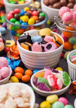 Meyan kökü şekerlemeleri, beyaz seramik tabağa karıştırılmış şekerler, jöle şekerleri ve kabuklu çikolata şekerleri.