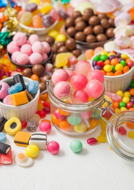 Kavanozda pembe lolipop şekerlemeleri çeşitli sütlü çikolata ve jöleli sakızlı şekerler üzerine beyaz meyankökü ve çilekli şekerler.